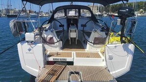 Eine Segelyacht mit überdachtem Deck, einem Suzuki Außenbordmotor und dem Namen 'NINNA NANNA' auf dem Bug.