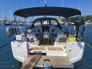 Eine Segelyacht mit überdachtem Deck, einem Suzuki Außenbordmotor und dem Namen 'NINNA NANNA' auf dem Bug.