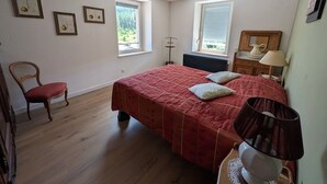 Ein Schlafzimmer mit einem Bett, einem Sessel, einer Heizung und zwei Fenstern.