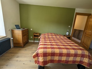Ein Schlafzimmer mit einem Bett, einem Schminktisch, einem Heizkörper, einer Lampe und einem Laptop auf dem Schminktisch.