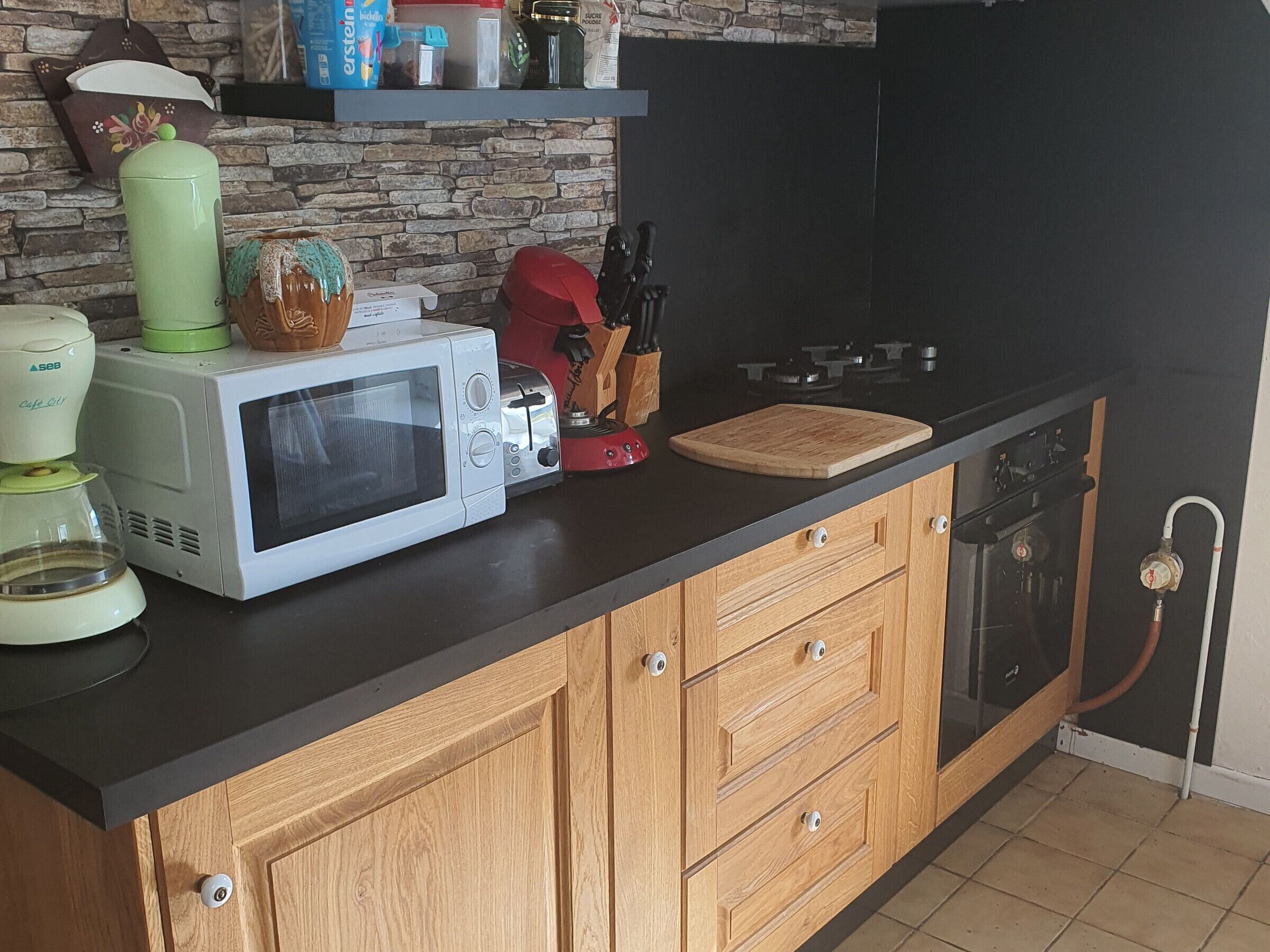 Een keuken met een magnetron, broodrooster en lades met houten aanrecht.