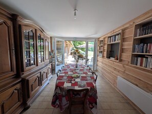 Een eetruimte met een lange tafel, houten kasten en boekenkasten.