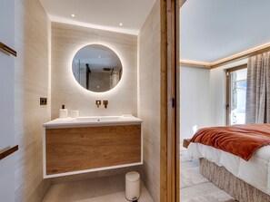 Ein modernes Badezimmer mit einem Holzkosmetikschrank, einem runden Spiegel und einer Toilette.