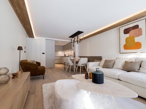 A modern living room with a sofa, a coffee table, and a dining area with chairs. - Apartment with parking - 4 guests (Val-d'Isère)