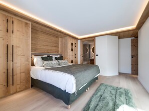 A modern bedroom with a wooden headboard, a large bed, and a green rug. - Apartment with parking - 4 guests (Val-d'Isère)