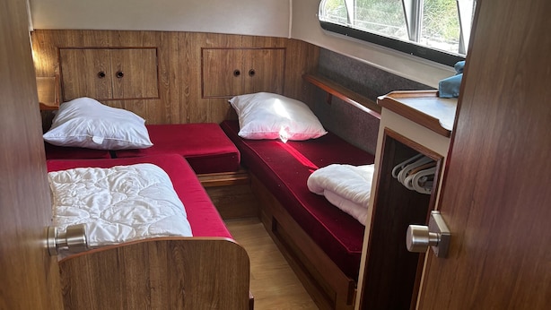 A compact cabin with two beds, a small seating area, and a window providing natural light.