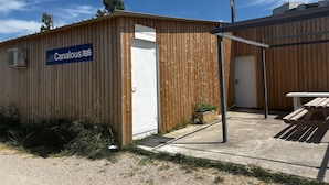 A wooden building with a sign reading 'LesCanalous' and a door labeled 'BUREAU D'ACCUEIL'.