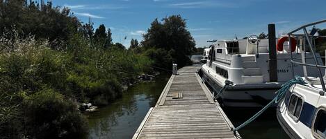 A wooden dock extending into a calm river, with a boat docked on the right.