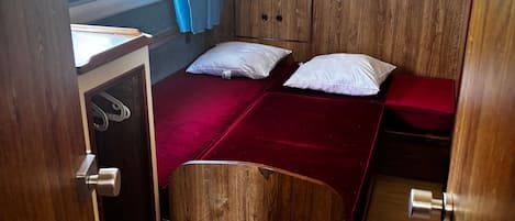 Una habitación pequeña y acogedora con dos camas, un armario de madera y una ventana con cortinas.
