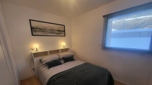 Ein Schlafzimmer mit einem Bett, Nachttischlampen, einem Fenster und einem Bild an der Wand.