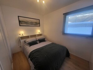 Ein Schlafzimmer mit einem Bett, Nachttischlampen, einem Fenster und einem Bild an der Wand.