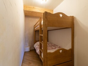 Ein Schlafraum mit Etagenbetten, Holzkopfteilen und einem kleinen Fenster.