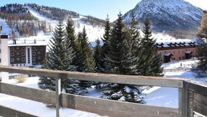 Blick auf Berge mit schneebedeckten Bäumen und einem Gebäude mit geneigtem Dach.