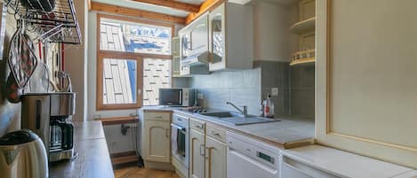 Cocina compacta con vigas de madera, un lavamanos, microondas y lavavajillas.