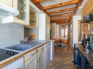Eine Küche mit Holzbalken, einem Spülbecken, einem Herd und einem Essbereich mit Stühlen.