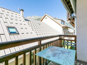 Ein Balkon mit Holzbalkon, einem Tisch mit Blumenmuster und Blick auf ein Gebirge.