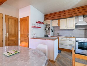 Eine kleine Küche mit Holzausstattung, einem Einbauofen und einem Essbereich mit Tisch und Stühlen.