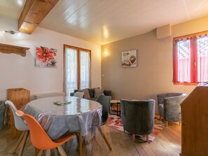 Ruokailutila, jossa on pyöreä pöytä, tuoleja, sohva ja puinen katto.