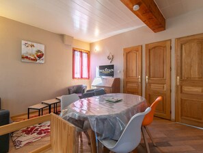 Ein Essbereich mit einem runden Tisch, Stühlen, einem Fernseher und Holztüren.