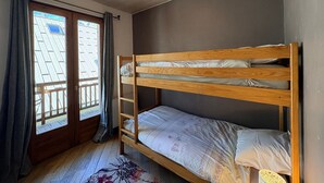 Kerrossängyllä varustettu huone, jossa on ikkuna, verhot ja kattovalaisin.