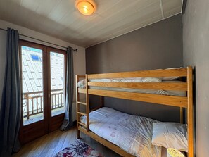 Ein Schlafraum mit Etagenbetten, einem Fenster, Vorhängen und einer Deckenleuchte.