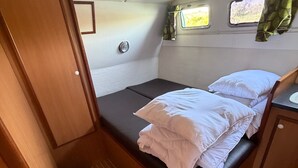 A compact RV bedroom with a bed, a small window, and a door.