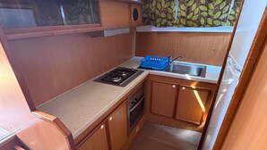 A compact kitchenette with a gas stove, oven, and a sink.