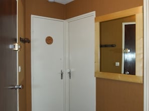 A closed white door with a circular emblem, a wooden-framed mirror, and a wooden door frame. - Central apartment, parking - 4 guests (Montgenèvre)