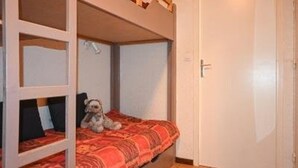 Ein Stockbett mit einem Hund auf der unteren Liege, einer Tür rechts und einem Fliesenboden.