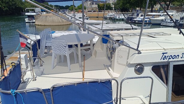 A boat with a white deck, blue seating, and a table. - Discover our boat in Cognac - 7 to 9 guests (Cognac)