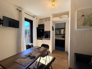 A compact living space with a dining area, kitchenette, and a small seating area. - Cozy studio in the heart of the station (Le Monêtier-les-Bains)