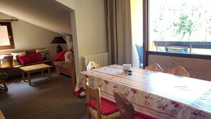 A cozy dining area with a table set for two, a wooden bench, and a chair with red cushions. - Loft apartment on the slopes - 4 guests (Montgenèvre)