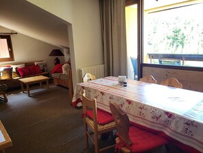 A cozy dining area with a table set for two, a wooden bench, and a chair with red cushions. - Loft apartment on the slopes - 4 guests (Montgenèvre)