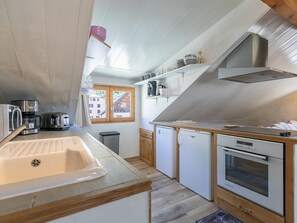 Una cocina compacta con lavamanos, cafetera, tostadora y horno integrado.