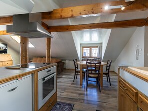 Una cocina con vigas de madera, una mesa de comedor con sillas, una estufa y un refrigerador.