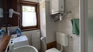 A compact bathroom with a toilet, sink, and shower. There is a window providing natural light and a towel hanging on the wall. - Apartment in central Montgenèvre - 4 guests (Montgenèvre)