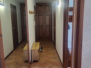 Um corredor estreito com portas de madeira e um banco.