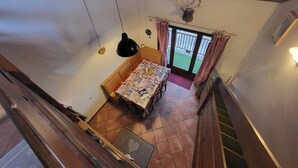 Una habitación con cama, una mesa con colcha, ventilador de techo y vista al exterior.