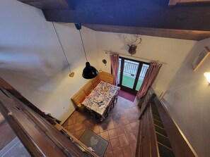 Ein Zimmer mit einem Bett, einem Tisch mit einer Steppdecke, einem Deckenventilator und Blick ins Freie.