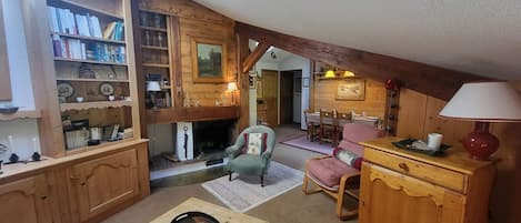 Un accogliente soggiorno in legno con camino, angolo da pranzo e libreria piena di libri e oggetti decorativi.
