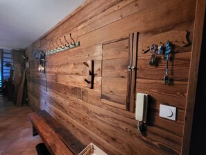 Eine Holzwand mit Kleiderhaken, zwei Schränken und einem Telefon.