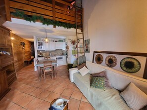 Ein gemütliches Wohnzimmer mit einer Couch, einem Esstisch und einer Küche im Hintergrund.