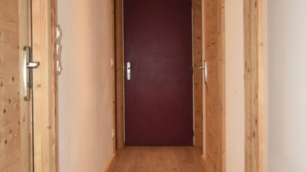 Un couloir aux murs en bois, avec une porte fermée au bout.