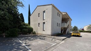 Ein Gebäude mit Parkplatz, einem gelben Auto und einer Treppe, die zu einer oberen Ebene führt.
