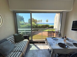 A balcony with a dining table, chairs, and a sofa. - Cozy apartment with parking, sea view - 4 guests (Sanary-sur-Mer)