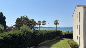Ein Küstenanwesen mit befestigter Auffahrt, üppiger Bepflanzung und Meerblick.