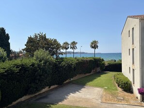 A coastal property with a paved driveway, lush greenery, and a view of the sea. - Cozy apartment with parking, sea view - 4 guests (Sanary-sur-Mer)