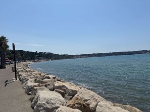 A coastal road with a rocky breakwater, clear skies, and a calm sea. - Cozy apartment with parking, sea view - 4 guests (Sanary-sur-Mer)