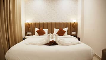 Habitación de hotel con una cama grande, dos lámparas de pared y un papel tapiz estampado con motivos florales.