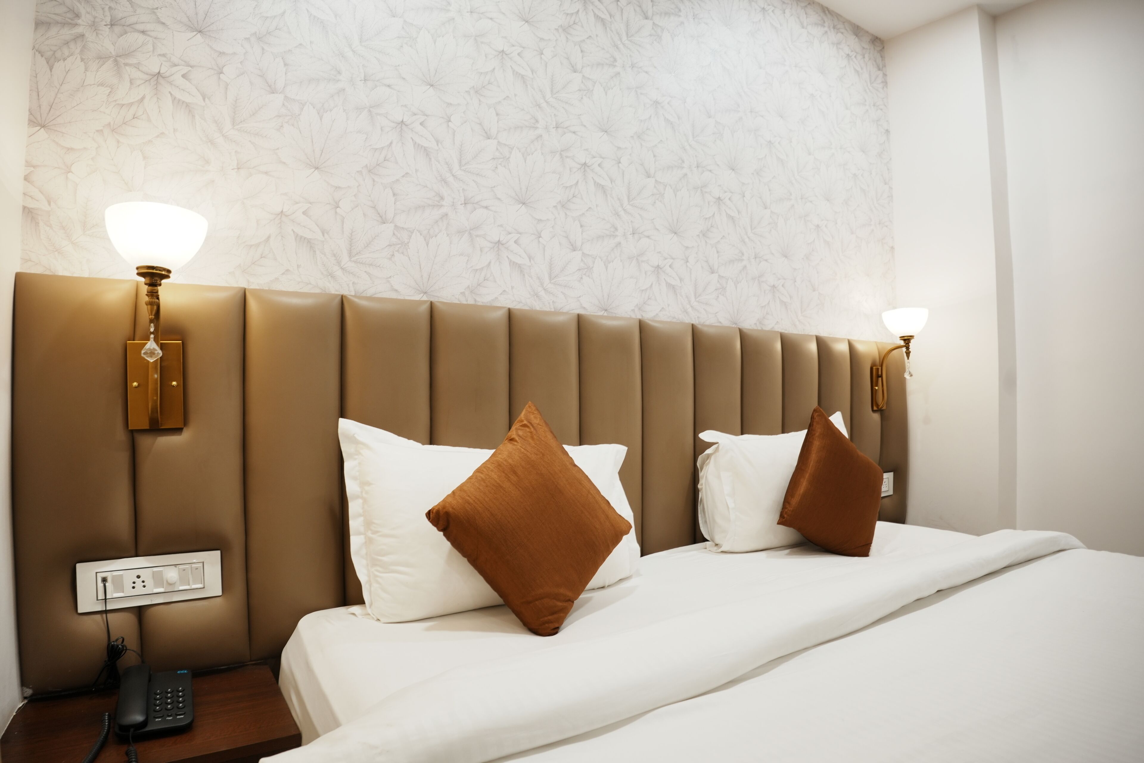 A hotel room with a large bed, two wall-mounted lamps, and a telephone on a bedside table.